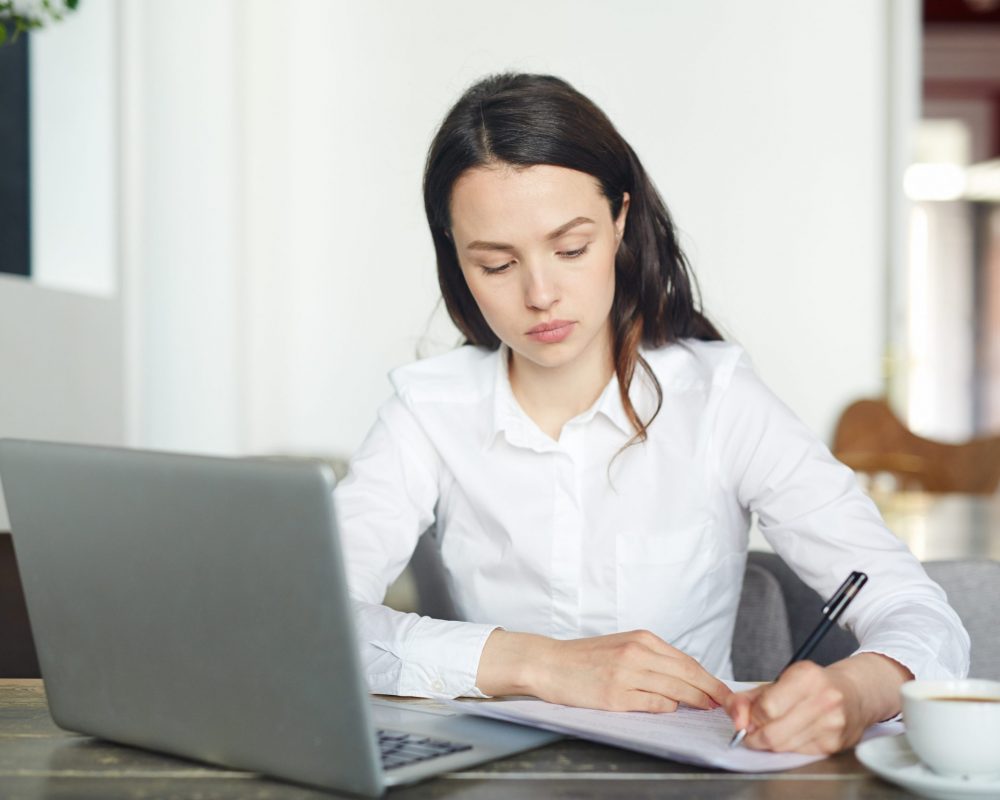 Young businesswoman signing papers and networking in cafe