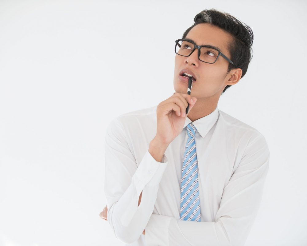 Closeup portrait of thoughtful adult business man looking away and biting pen. Isolated view on white background.