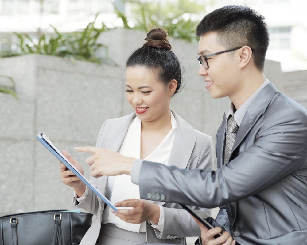 Smiling Vietnamese business executive discussing details of contract